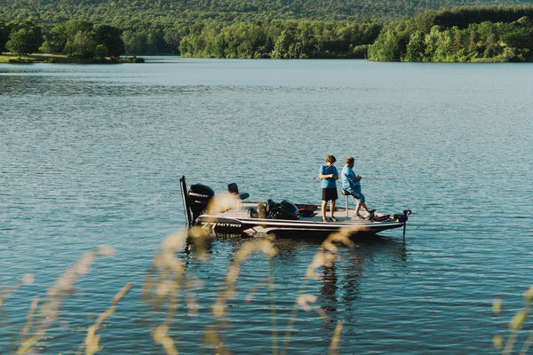 a-group-of-people-standing-on-top-of-a-boat-on-a-lake