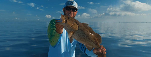 the fisherman holds the big fish he caught